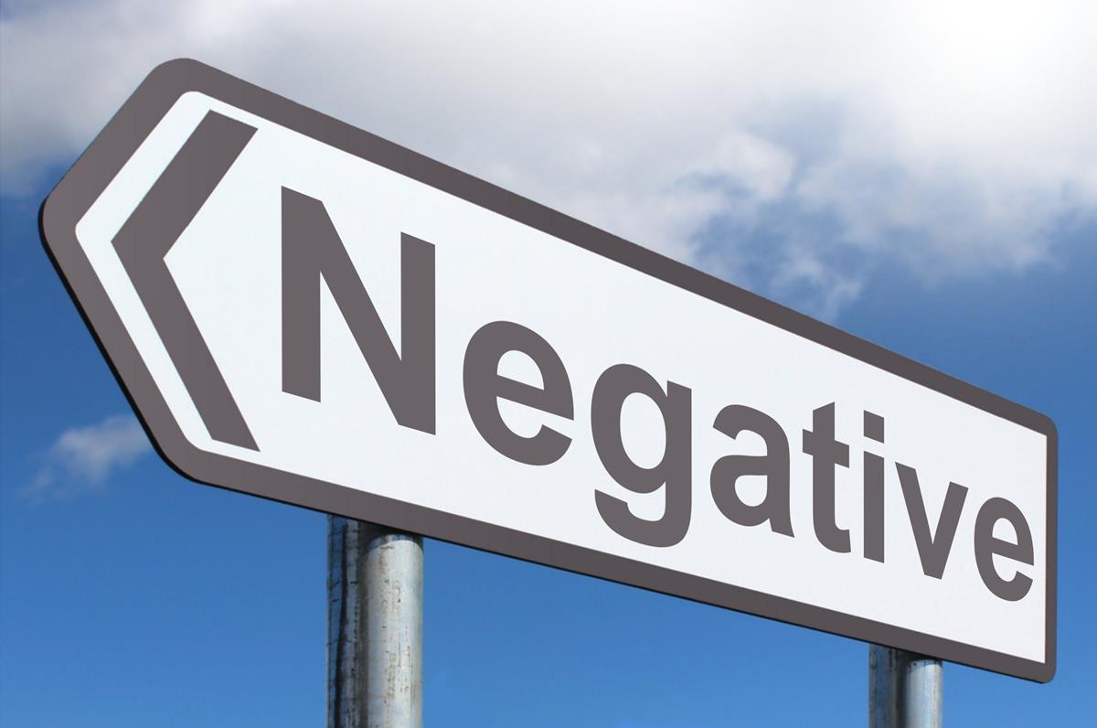  A road sign with the word 'Negative' in bold letters pointing to the left with a cloudy blue sky in the background.